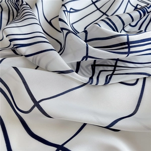 Detail of soft silk-like scarf featuring dark blue geometric lines on white fabric