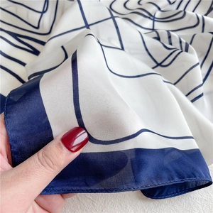 Minimalist square silk scarf with navy geometric lines and elegant satin finish