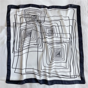 Detailed view of square silk scarf featuring black geometric spiral lines on white fabric