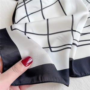 Close-up of a black and white grid silk scarf showing smooth satin texture and fine drape