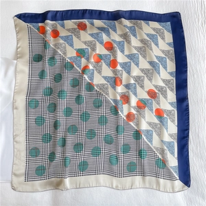 Detail view of silk-like square scarf featuring houndstooth and paisley patterns