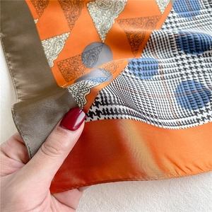 Detailed view of paisley and houndstooth patterned silk scarf with premium texture