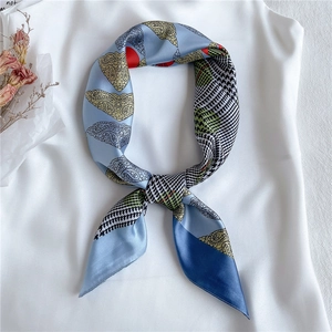 Macro detail of sky blue faux silk square scarf featuring paisley and houndstooth patterns
