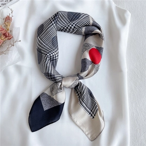 Silk-feel scarf with houndstooth, paisley and red polka dots tied as a bow over a white top