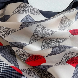 Macro shot of faux silk square scarf with red polka dots and black paisley patterns