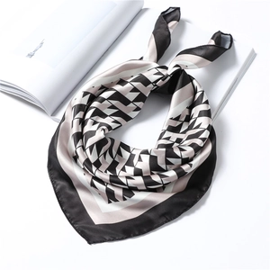 Detail of geometric pattern silk scarf with black borders folded on a magazine