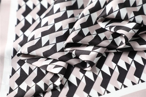 Detail of silk-like geometric scarf with black, white, and pink patterns and smooth texture