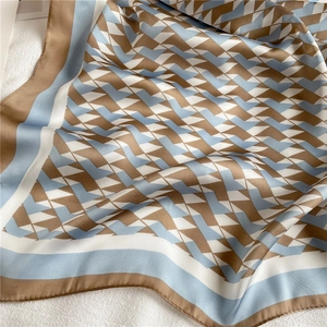Macro detail of geometric patterned faux silk scarf with brown and blue blocks