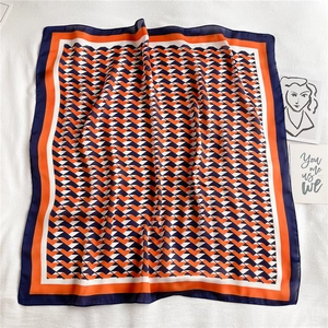 Flat lay of geometric color-block silk-like square scarf with orange and blue triangle patterns