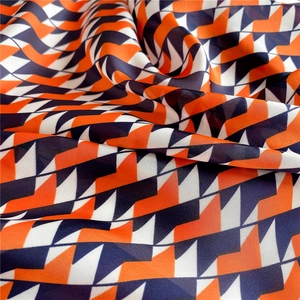 Detail of the high-quality geometric silk scarf fabric with vibrant orange and navy tones