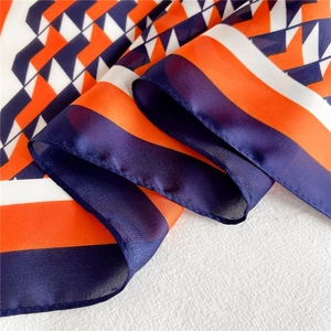 Close-up of geometric pattern silk scarf with orange and navy blue triangle print