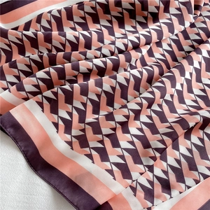 Macro detail of geometric V-pattern silk scarf in coral pink, cream white and dark purple