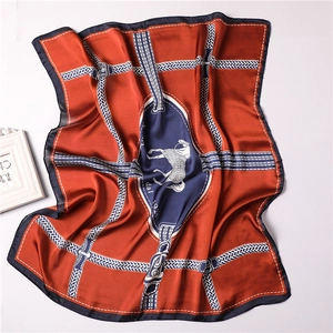 Detailed view of luxury silk-like square scarf featuring classic orange horse motif patterns