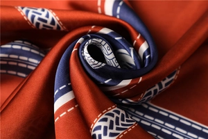 Macro shot of satin silk scarf with orange and navy geometric patterns and glossy finish