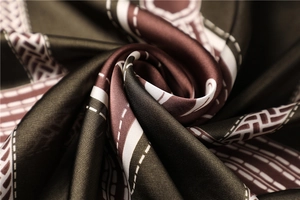 Macro shot of silk satin scarf featuring vintage geometric patterns in burgundy and brown