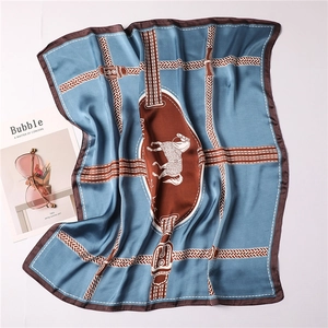 Detailed close-up of blue silk scarf featuring vintage horse patterns and leather strap motifs