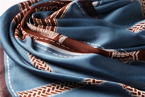 Detail of silky vintage blue scarf with geometric patterns and AMOR print texture