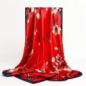Vue détaillée d'un foulard en soie rouge avec fleurs de magnolia et bordure bleu marine