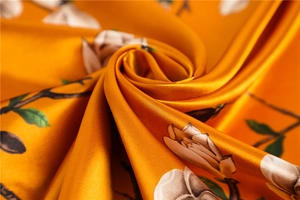 Détail du foulard carré au toucher soie avec imprimé magnolia orange et texture satinée