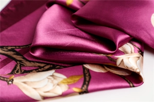 Gros plan d'un élégant foulard en satin magenta avec des motifs de fleurs de magnolia