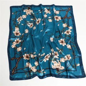Détail du foulard satiné bleu foncé aux fleurs de magnolia blanches et texture soyeuse