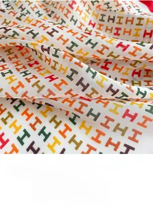 Nahaufnahme eines Seidenquadrats mit buntem H-Muster und glatter, seidiger Textur