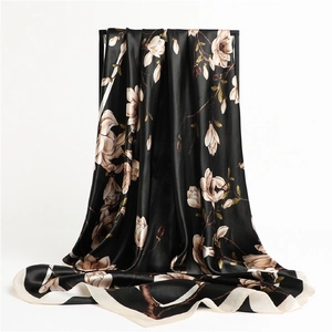 Détail d'un foulard en satin soyeux avec élégant imprimé de magnolia blanc sur noir