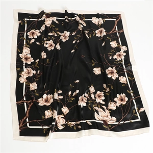 Vue détaillée du motif élégant de magnolia sur un foulard carré noir au toucher soie