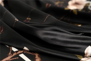Détail macro du tissu en soie noire avec imprimé floral vintage et texture satinée
