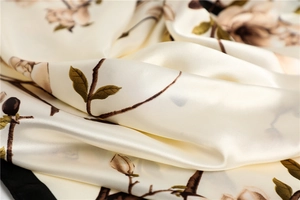 Gros plan d'un foulard carré en soie crème avec un imprimé floral de magnolia vintage