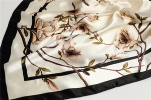 Détail d'un carré de soie aux imprimés élégants de magnolia avec des bords noirs contrastés