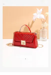 Close-up of red patent leather shoulder bag with V-quilted pattern and gold turn-lock