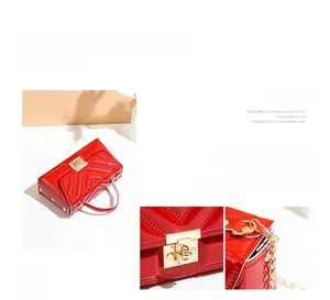 Close-up of bright red patent leather handbag with V-shaped stitching and gold metal lock