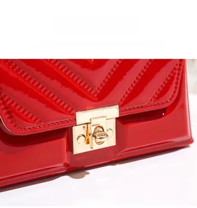 Detail of red patent leather handbag with V-shaped quilting and gold metal buckle