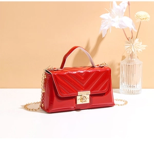 Macro shot of red quilted patent leather handbag with gold clasp and chain strap