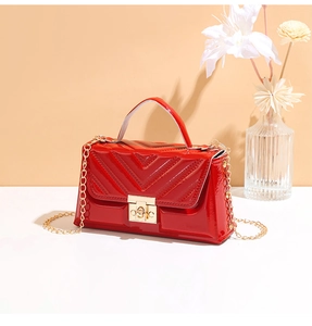 Close-up of red patent leather crossbody bag with V-quilt pattern and gold metal clasp