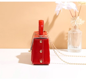 Side view of red quilted patent leather crossbody bag with gold stud details
