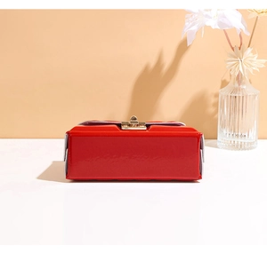 Close-up of red patent leather square crossbody bag with elegant gold metal clasp