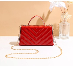 Close-up of red patent leather handbag featuring elegant V-shaped quilting and gold chain