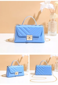 Detailed macro view of glossy blue jelly bag with gold V-quilt pattern and chain strap