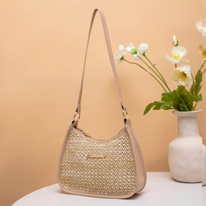 Detail of woven straw texture and gold metal logo on beige leather shoulder bag