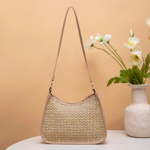 Detailed view of woven straw shoulder bag with leather trim and gold zipper accents
