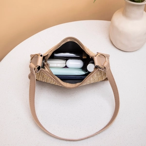 Straw shoulder bag for women showing spacious interior with daily essentials on marble
