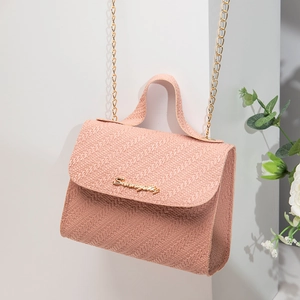 Pink textured square handbag with gold chain strap and top handle on geometric stand