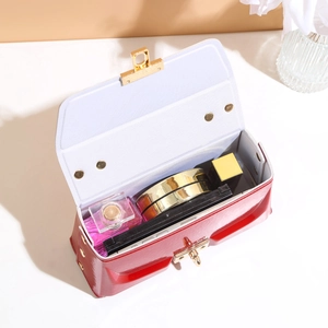 Elegant red patent leather crossbody bag with gold twist lock showing internal storage
