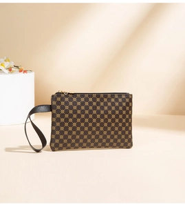 Detail of a brown water-ripple pattern clutch with gold zipper and black hand strap