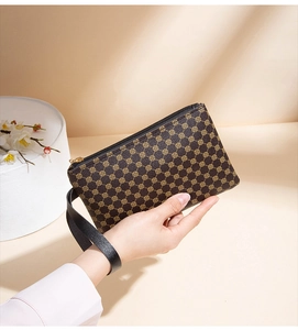 Close-up of brown floral patterned clutch with black leather strap and metal zipper