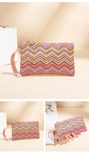 Detail of colorful zigzag woven clutch with pink wrist strap and gold zipper pull
