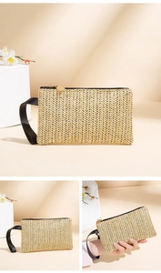 Detail of straw woven clutch bag with zigzag pattern, black wrist strap and gold zipper