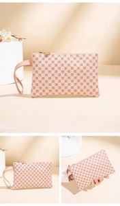 Close-up of pink woven clutch bag featuring brown floral patterns and golden hardware